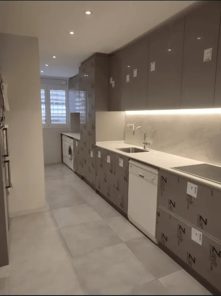 Reforma integral de cocina moderna con muebles altos y encimera blanca