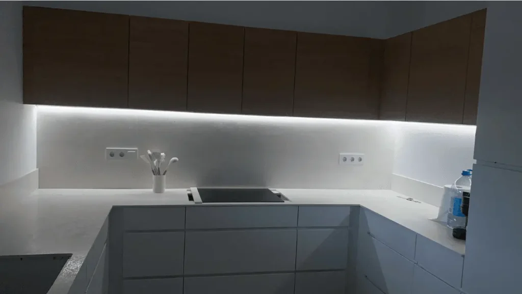 Iluminación LED lineal en cocina blanca con mobiliario lacado y armarios de madera