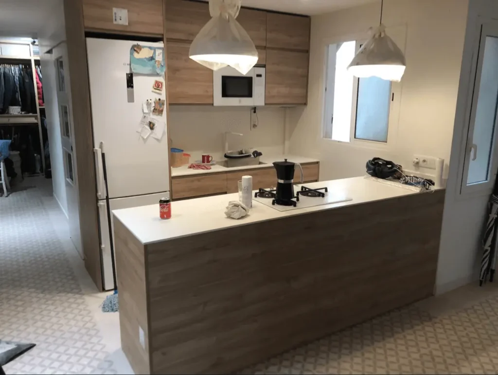 Cocina office reformada con barra de madera, encimera blanca y mobiliario a medida.