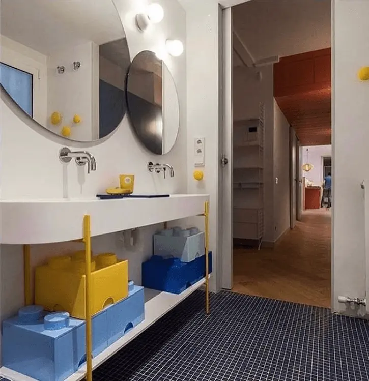 Lavamanos doble de diseño moderno con grifos empotrados y sistema de almacenaje en forma de bloques de construcción de colores amarillo y azul.