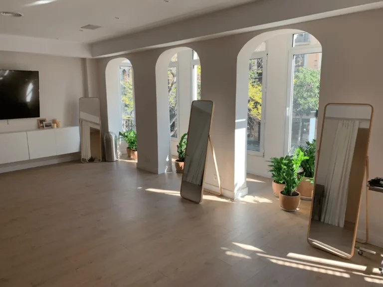 Sala diáfana con suelo de madera clara, paredes blancas y grandes ventanales arqueados.