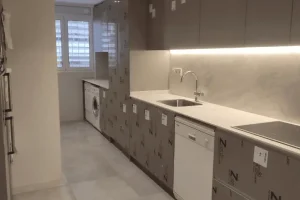 Reforma integral de cocina moderna con muebles altos y encimera blanca