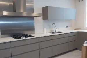 Cocina moderna en tonos gris mate con campana de acero inoxidable y encimera blanca