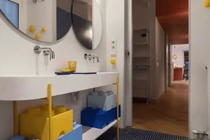 Lavamanos doble de diseño moderno con grifos empotrados y sistema de almacenaje en forma de bloques de construcción de colores amarillo y azul.